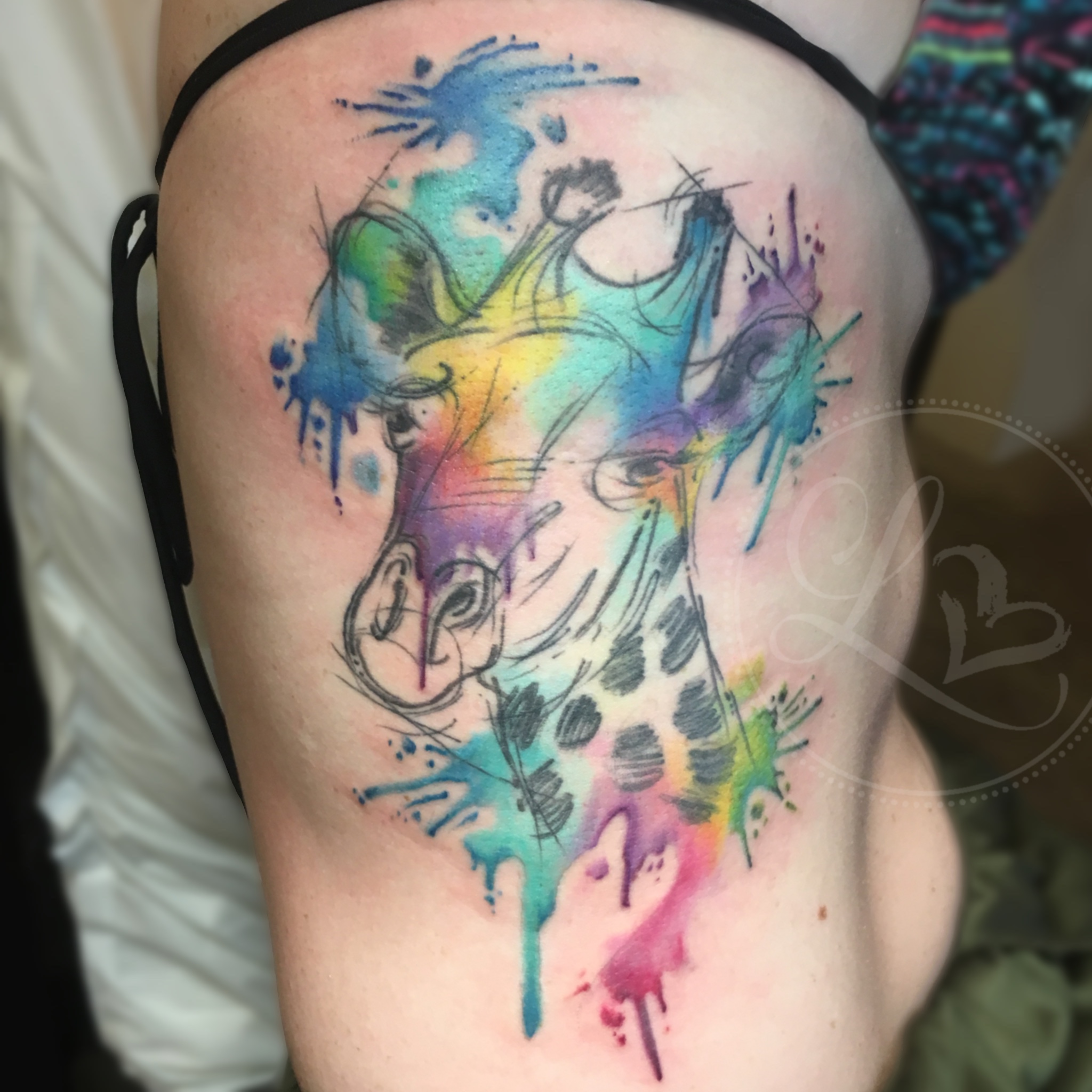 Colorful watercolor style giraffe tattoo on the ibs