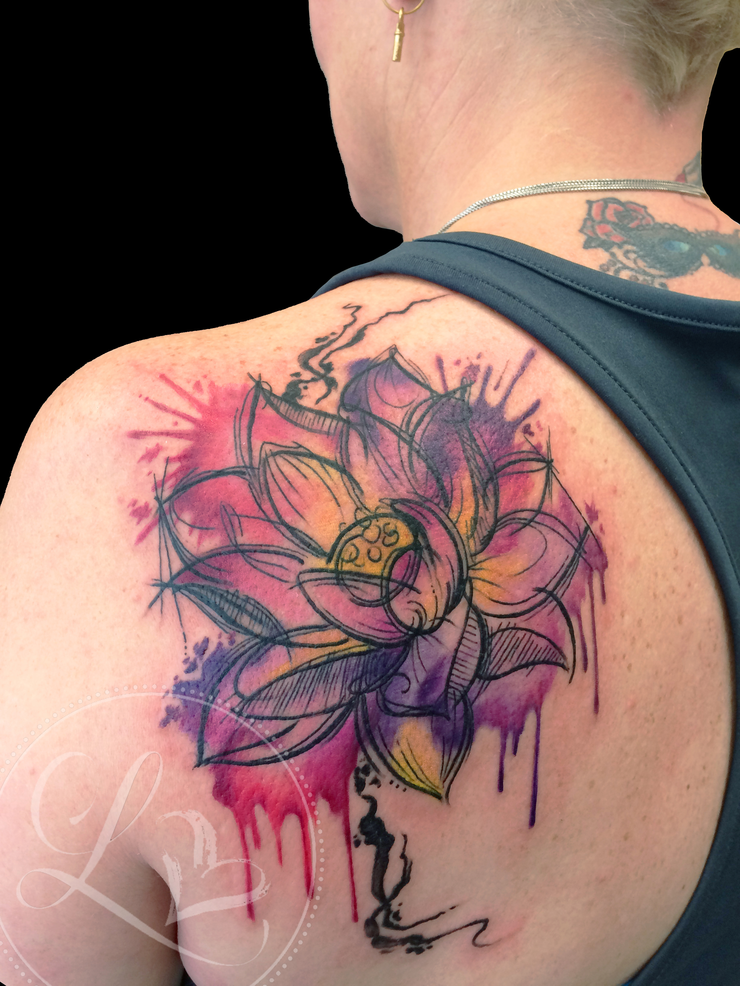 Colorful watercolor style lotus tattoo on a woman's scapula with sketchy linework