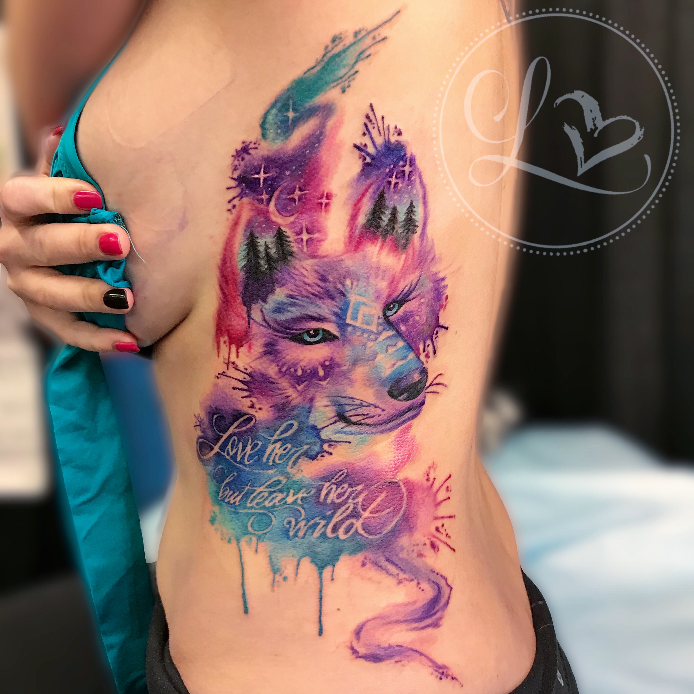 Colorful watercolor style ribcage side tattoo of a wolf and lettering