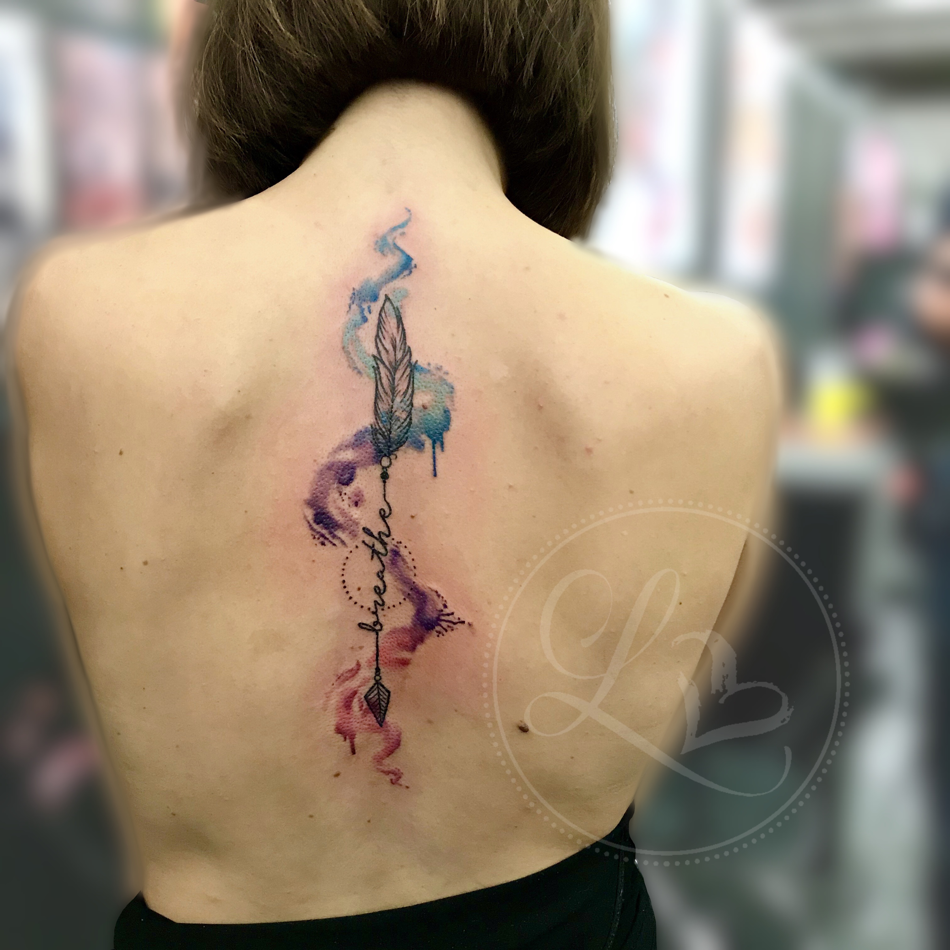 Watercolor splash and ornamental arrow spine tattoo