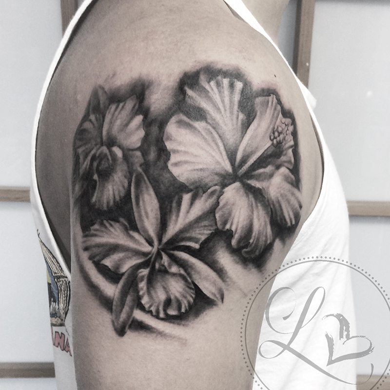 Realistic black and grey tattoo of tropical flowers hibiscus and orchid on a man's shoulder